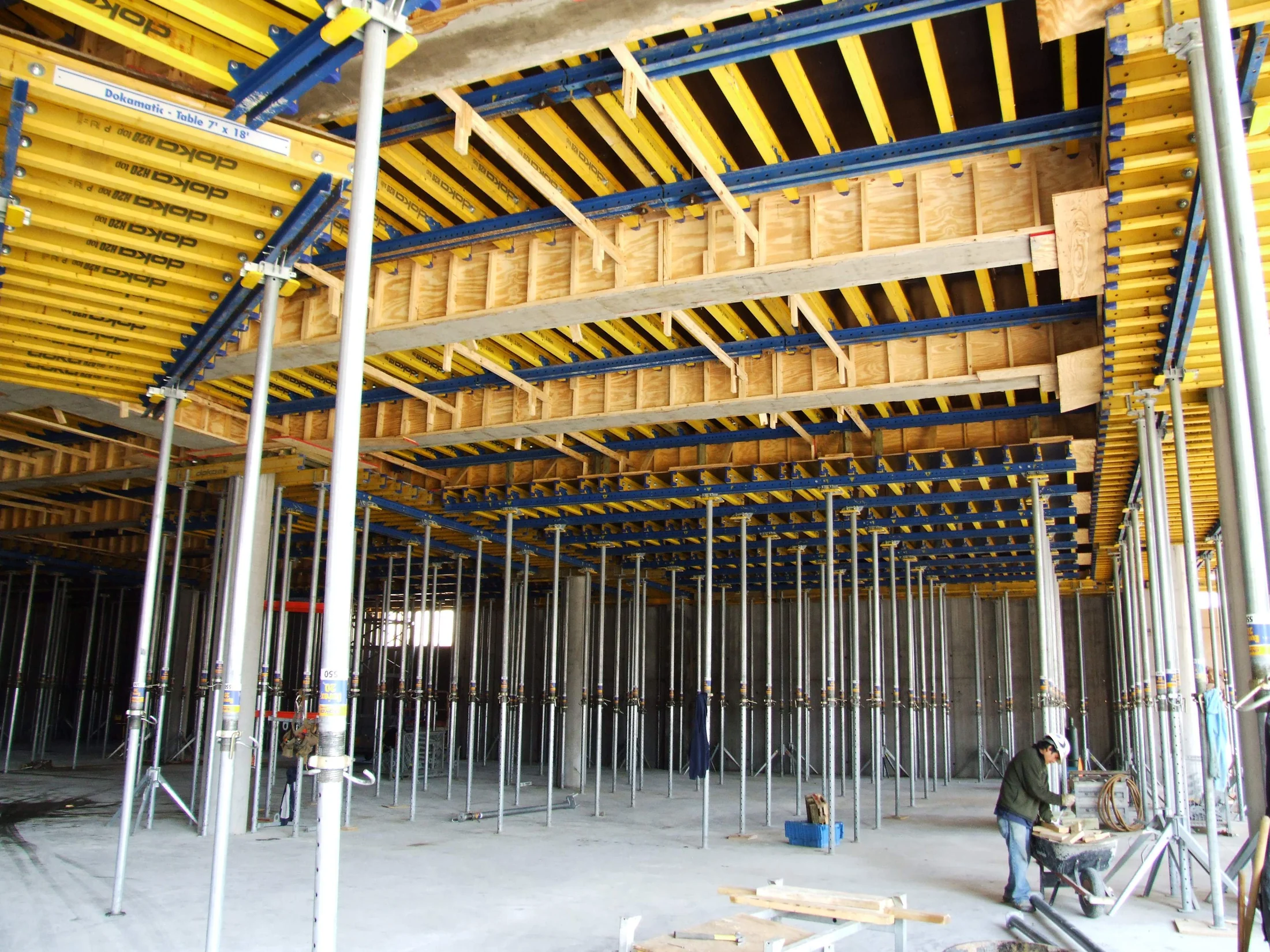 Timber beams, plywood forms and adjustable steel props supporting a concrete slab under construction